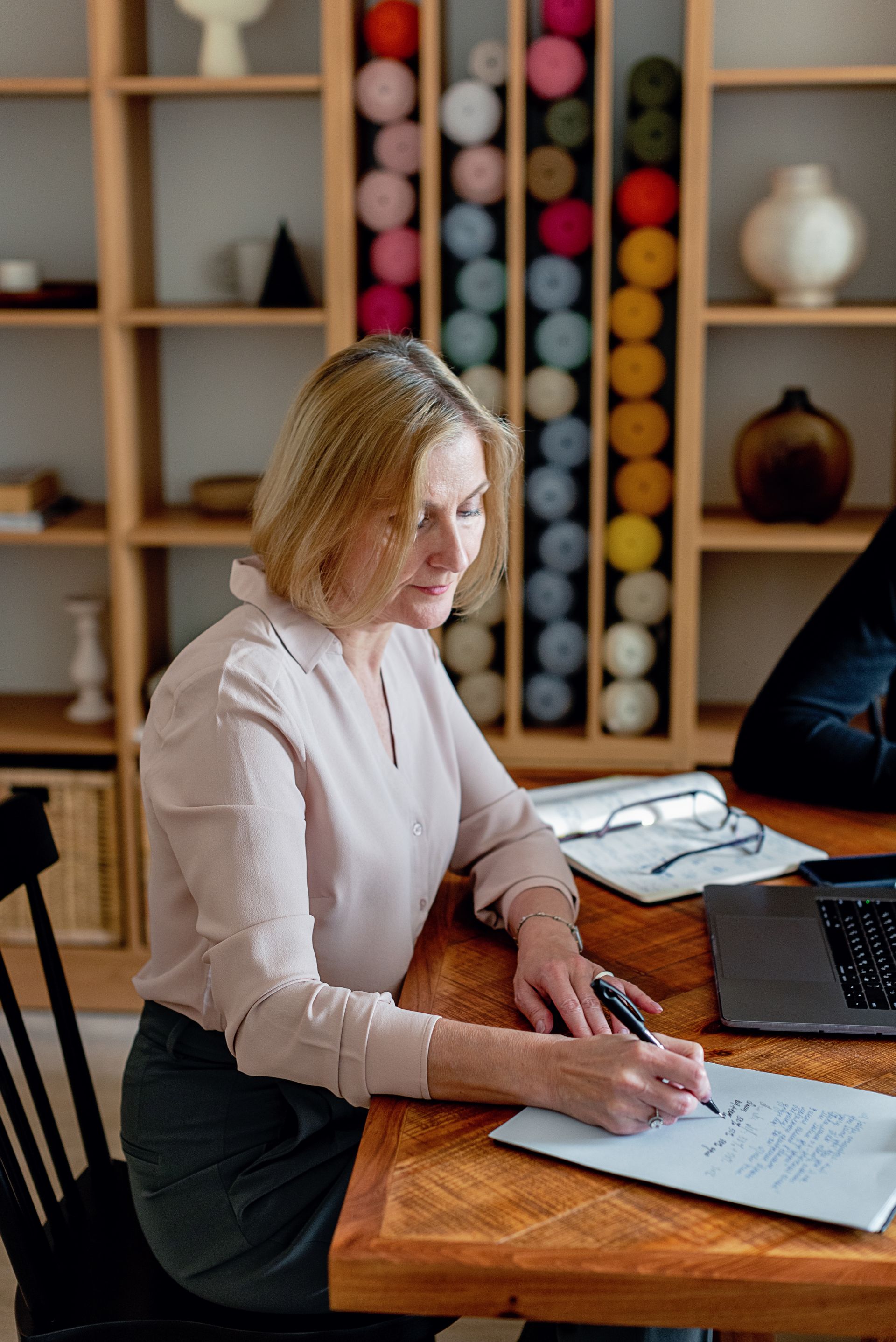A woman writing notes at her desk