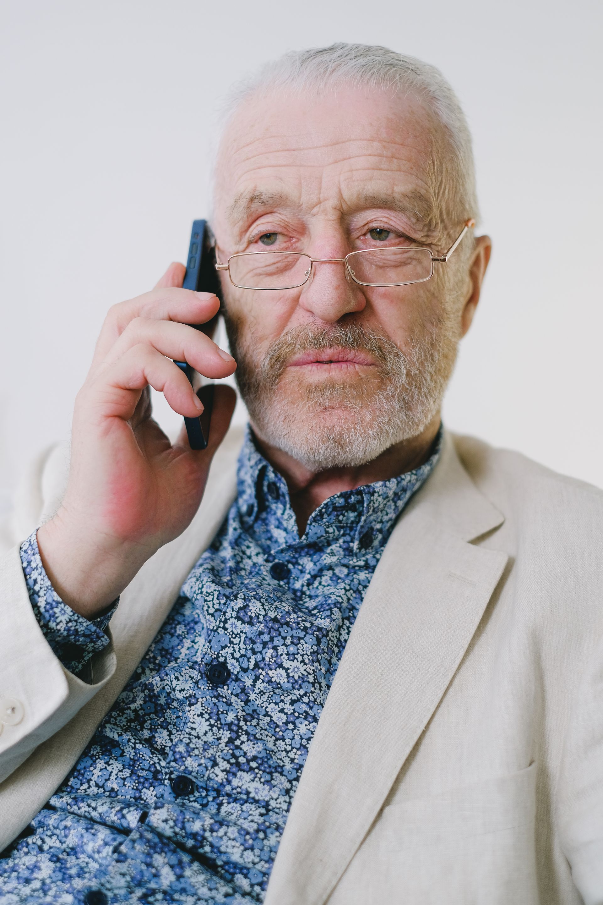 An older man in a linen jacket taking a phone call