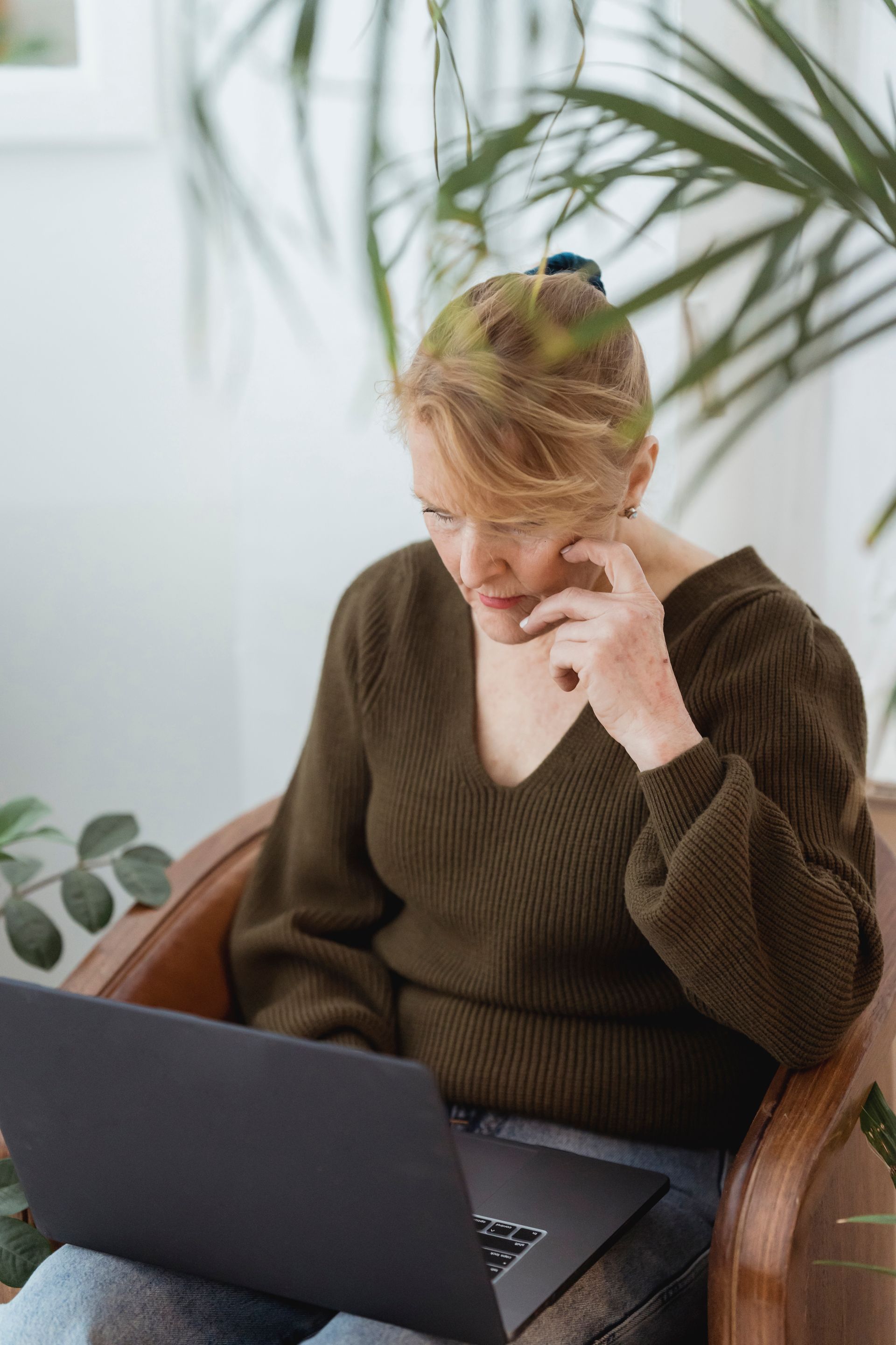 A woman concentrating on her laptop in an armchair