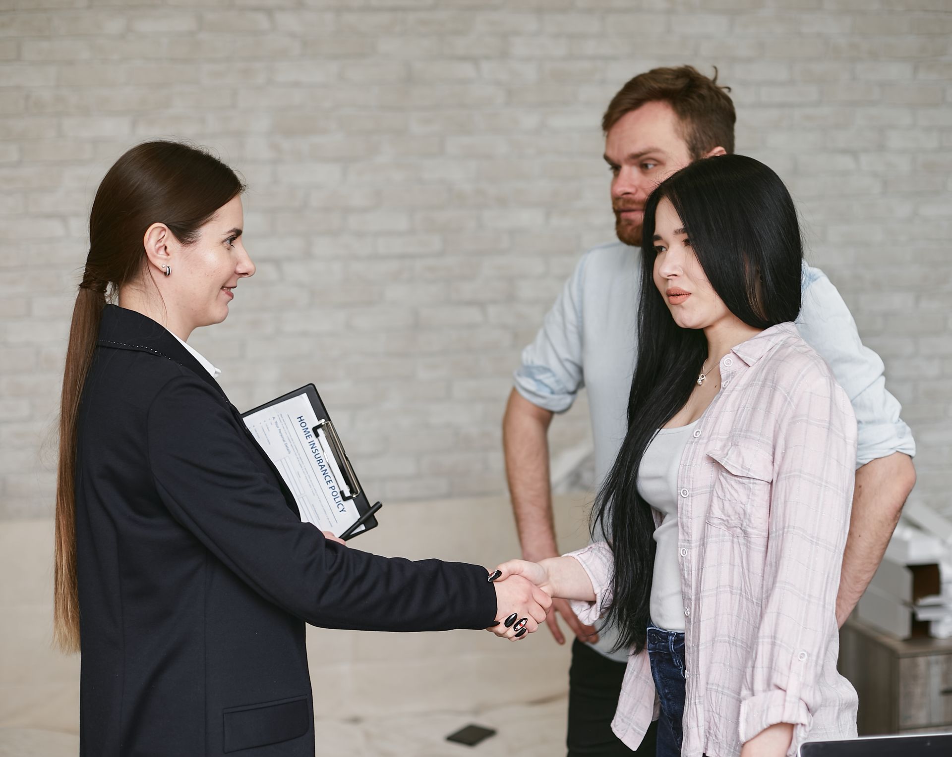 A professional woman greeting clients with a handshake